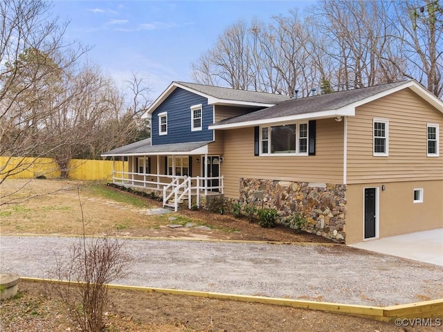 view of front of home with gravel driveway, a porch, and a shingled roof