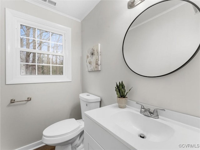 half bathroom with visible vents, toilet, ornamental molding, baseboards, and vanity