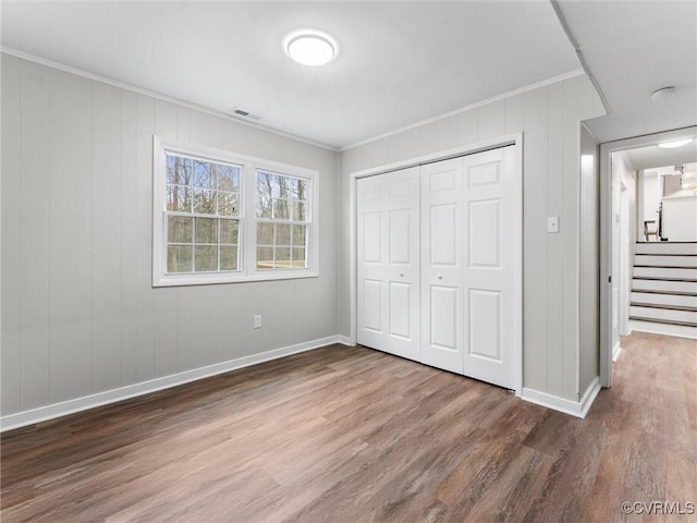 unfurnished bedroom featuring visible vents, wood finished floors, and ornamental molding