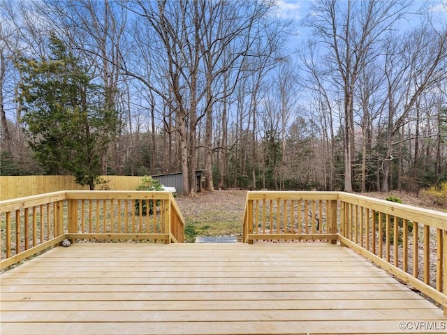 wooden terrace featuring a wooded view and fence