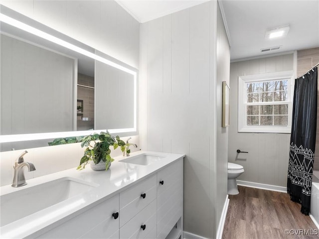 bathroom with a sink, visible vents, toilet, and wood finished floors