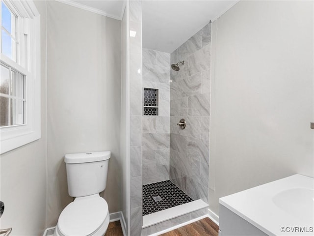 full bath with toilet, tiled shower, vanity, and wood finished floors