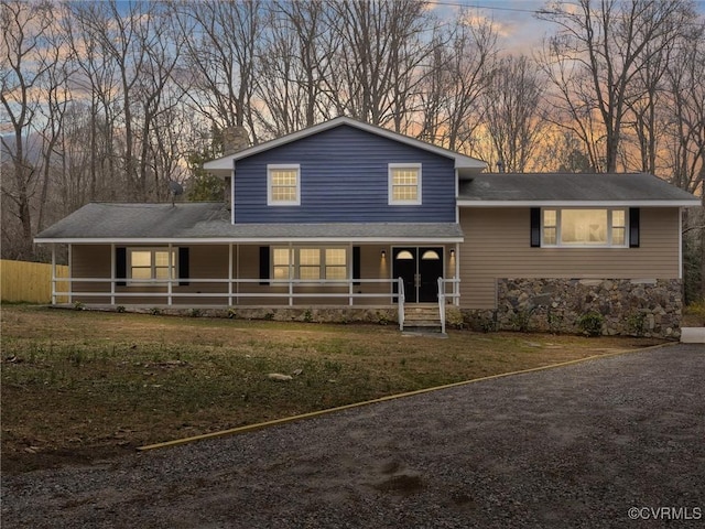 view of front facade with stone siding, a porch, and a front lawn