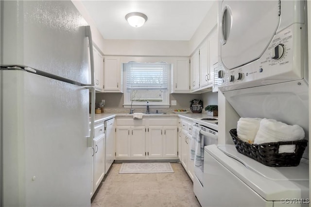 kitchen featuring white appliances, white cabinetry, light countertops, and stacked washer and dryer