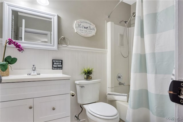 full bath with wainscoting, toilet, shower / bath combo, and vanity