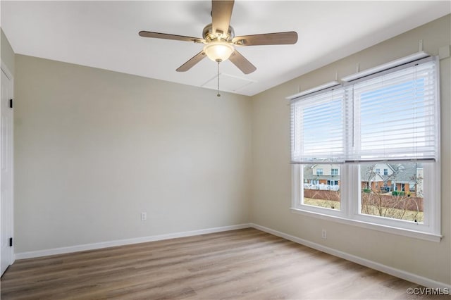 spare room with a wealth of natural light, ceiling fan, baseboards, and wood finished floors