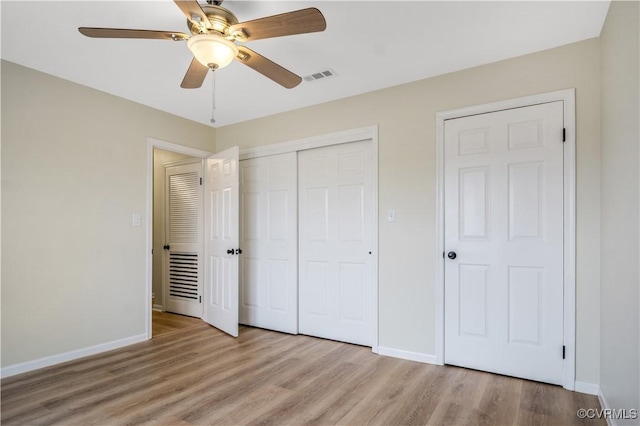 unfurnished bedroom featuring visible vents, ceiling fan, baseboards, wood finished floors, and a closet