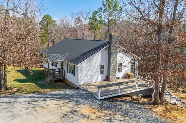 view of home's exterior with a chimney, a deck, and metal roof