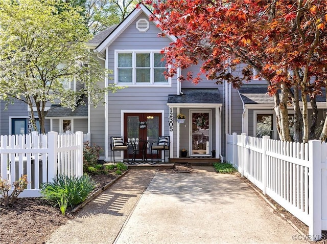 view of front of home with french doors, a shingled roof, and a fenced front yard