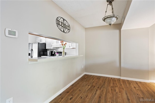 unfurnished dining area featuring dark wood-type flooring, baseboards, a sink, and lofted ceiling
