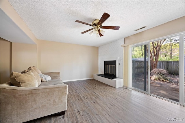 living room with visible vents, baseboards, a ceiling fan, a textured ceiling, and wood finished floors