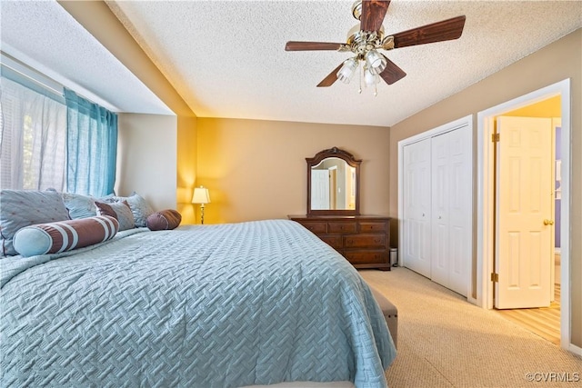 bedroom featuring a closet, light colored carpet, a textured ceiling, and ceiling fan