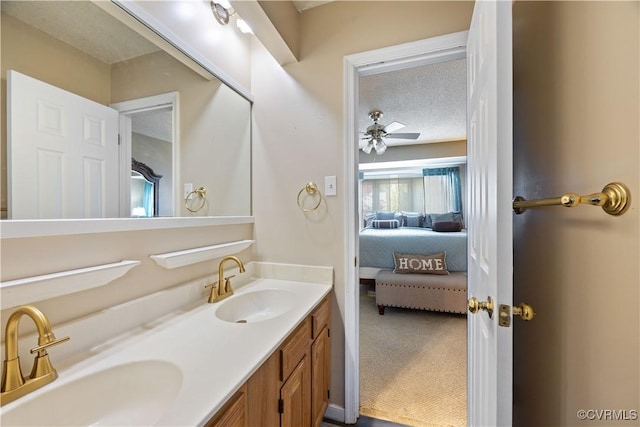 ensuite bathroom featuring ceiling fan, double vanity, a sink, and connected bathroom