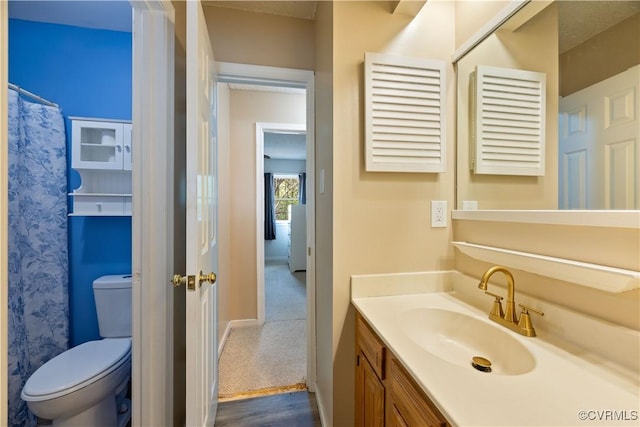 bathroom featuring toilet, vanity, wood finished floors, and baseboards