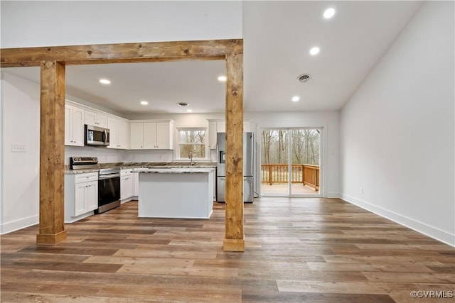 kitchen featuring wood finished floors, baseboards, visible vents, stainless steel appliances, and white cabinetry