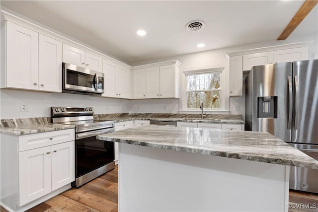 kitchen with visible vents, white cabinetry, stainless steel appliances, and wood finished floors