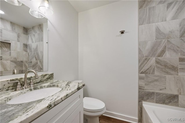 bathroom with toilet, vanity, baseboards, and wood finished floors