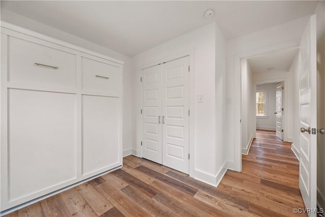 unfurnished bedroom with wood finished floors, a closet, and baseboards