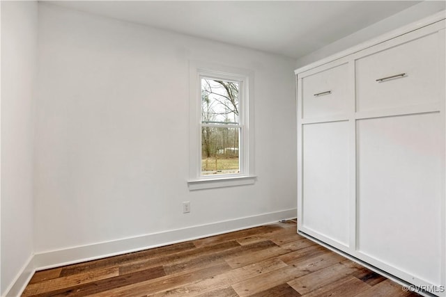 unfurnished bedroom with a closet, baseboards, and hardwood / wood-style flooring