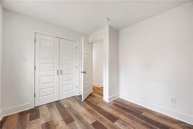 unfurnished bedroom with a closet, baseboards, and wood finished floors