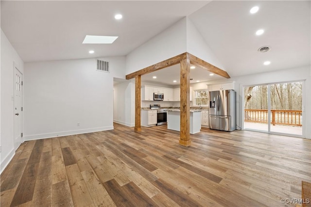 unfurnished living room with recessed lighting, visible vents, light wood-style floors, and a skylight