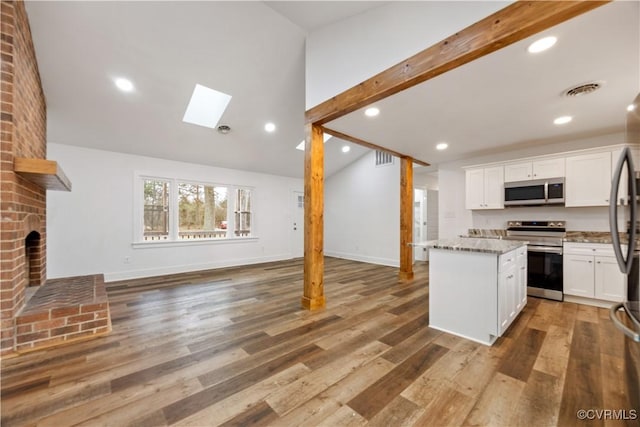 kitchen with a center island, light stone countertops, open floor plan, light wood-style flooring, and appliances with stainless steel finishes