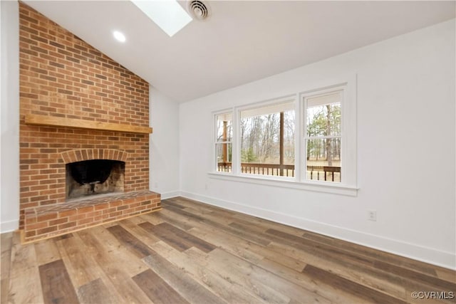 unfurnished living room featuring wood finished floors, visible vents, baseboards, a fireplace, and lofted ceiling with skylight