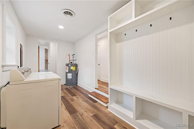 washroom with wood finished floors, visible vents, washing machine and clothes dryer, laundry area, and water heater