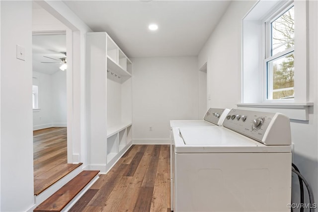 clothes washing area featuring a ceiling fan, laundry area, dark wood-type flooring, washing machine and dryer, and a wealth of natural light