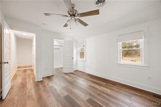 unfurnished bedroom with visible vents, multiple windows, baseboards, and wood finished floors