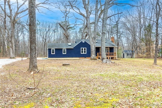 view of front of property with an outbuilding, a storage unit, and a chimney