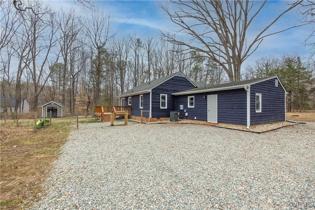 view of front of house with a deck, an outbuilding, and driveway