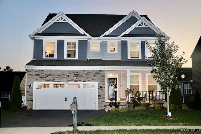view of front of property with a porch, an attached garage, stone siding, and asphalt driveway