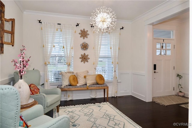 sitting room with wood finished floors, a chandelier, healthy amount of natural light, ornamental molding, and wainscoting
