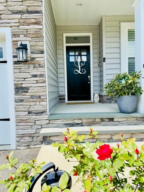 view of exterior entry with stone siding and a porch