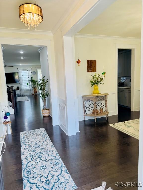 hallway featuring ornamental molding, a chandelier, and dark wood-style flooring