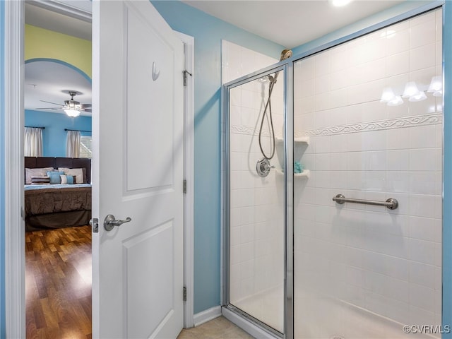 full bathroom with a shower stall, ensuite bathroom, a ceiling fan, and wood finished floors