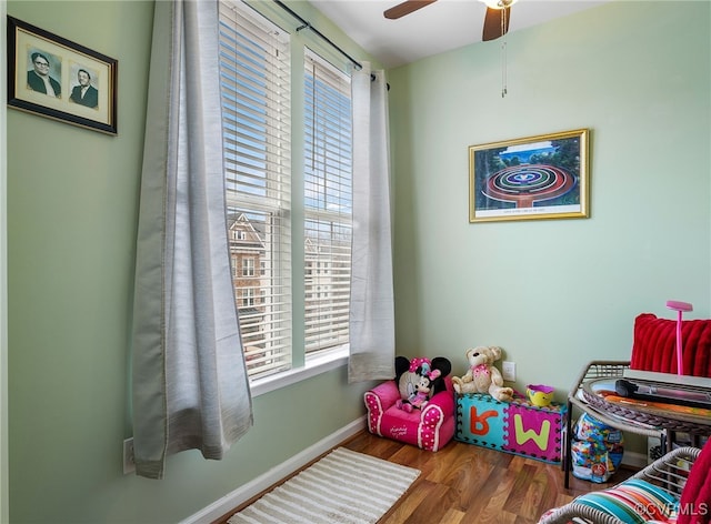 playroom featuring ceiling fan, baseboards, and wood finished floors