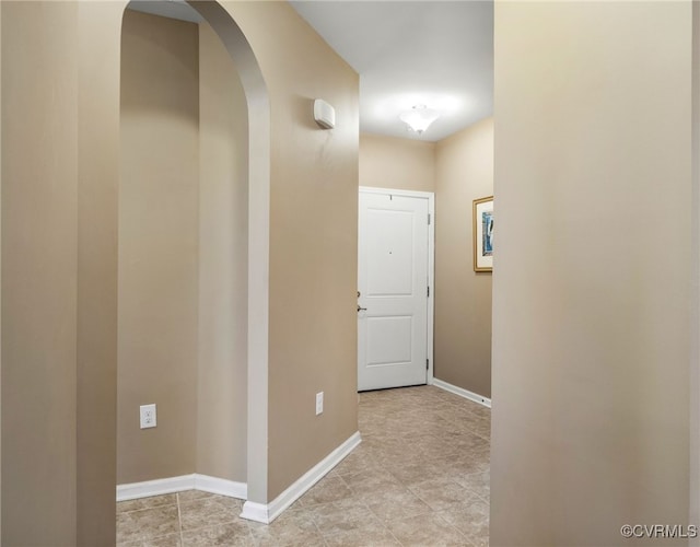 hallway with arched walkways and baseboards