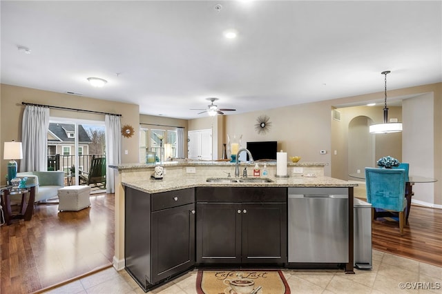 kitchen featuring light stone counters, ceiling fan, a sink, dishwasher, and open floor plan