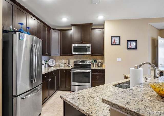 kitchen featuring light tile patterned floors, dark brown cabinets, backsplash, and appliances with stainless steel finishes