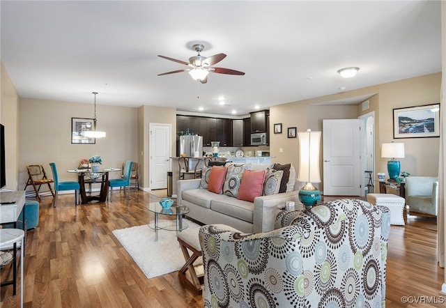 living area featuring baseboards, wood finished floors, and a ceiling fan