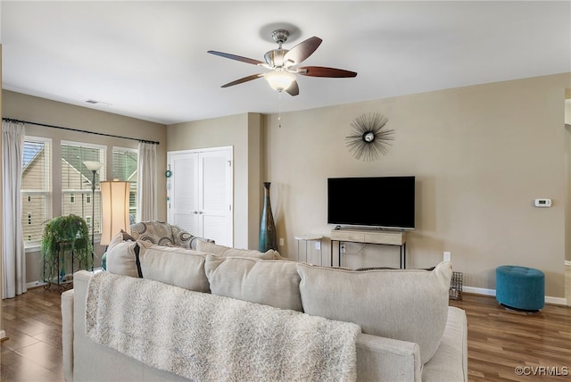 living room with wood finished floors, visible vents, baseboards, and ceiling fan