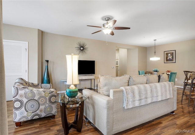 living area featuring ceiling fan, baseboards, and wood finished floors