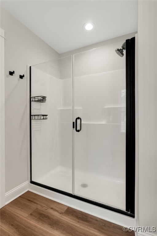 bathroom with baseboards, recessed lighting, a stall shower, and wood finished floors