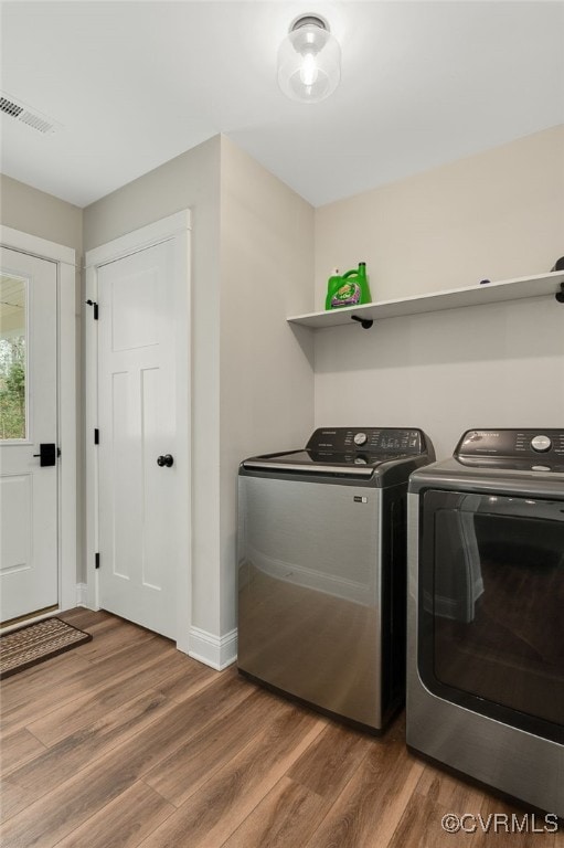 laundry area with baseboards, visible vents, laundry area, washer and dryer, and wood finished floors