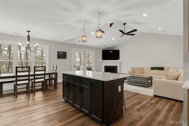 kitchen with a fireplace, a center island, lofted ceiling, ceiling fan with notable chandelier, and wood finished floors