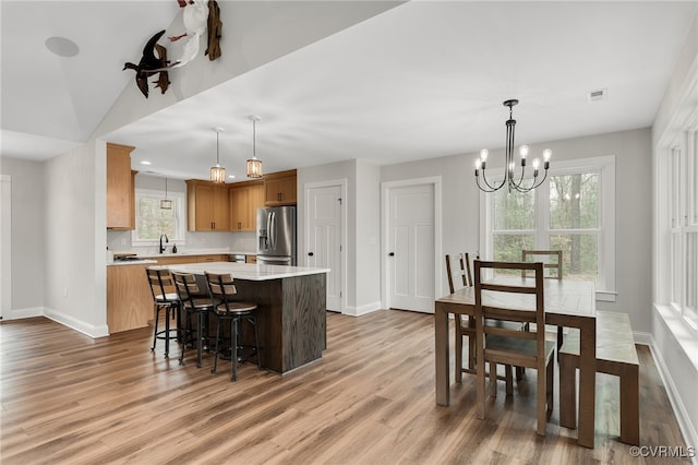 kitchen featuring stainless steel fridge with ice dispenser, visible vents, a kitchen island, light countertops, and baseboards