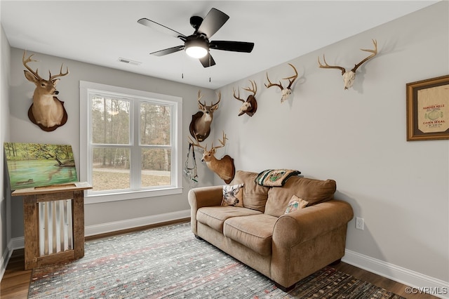 living area featuring visible vents, baseboards, ceiling fan, and wood finished floors