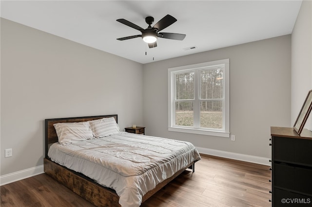 bedroom with visible vents, baseboards, a ceiling fan, and wood finished floors